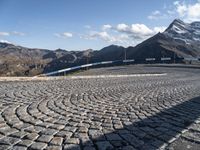 a road with cobblestone at the bottom and snowy mountains in the background,