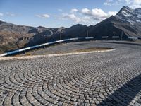 a road with cobblestone at the bottom and snowy mountains in the background,