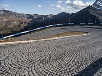 a road with cobblestone at the bottom and snowy mountains in the background,