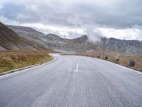 a large long empty road that leads to the top of a mountain with mountains and a sky in the background