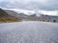 a large long empty road that leads to the top of a mountain with mountains and a sky in the background