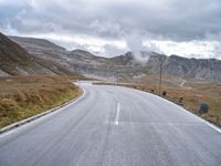 a large long empty road that leads to the top of a mountain with mountains and a sky in the background