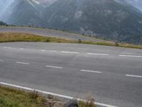 a person is riding a motorcycle down the road on a hill in front of mountains