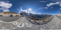 fish eye photo of a mountainous highway with cars driving along it from the top of a high mountain