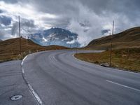 an asphalt road stretches into the distance with mountains in the background on a cloudy day