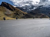 an asphalt road with mountain tops and a white van parked at the curb in front