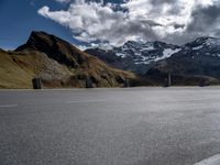 an asphalt road with mountain tops and a white van parked at the curb in front