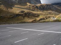 a view of mountains from an empty highway, in the middle of the frame, while it looks overcast