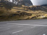 a view of mountains from an empty highway, in the middle of the frame, while it looks overcast