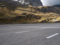 a view of mountains from an empty highway, in the middle of the frame, while it looks overcast