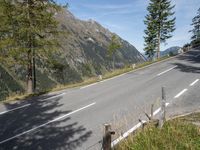 a black motorcycle driving on an empty street next to mountains and trees in a field