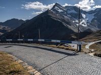 a person standing on the side of a mountain road next to a paved road with a bunch of poles and a sky