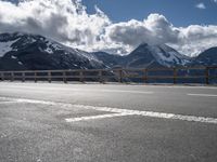 a person riding a bike on the side of a highway next to a mountain range