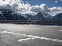 a person riding a bike on the side of a highway next to a mountain range