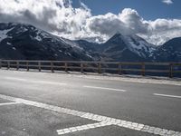 a person riding a bike on the side of a highway next to a mountain range