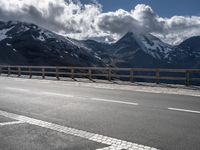 a person riding a bike on the side of a highway next to a mountain range