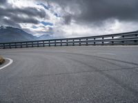 a highway stretches in the distance between two mountains, on a partly cloudy day with dark clouds