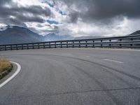 a highway stretches in the distance between two mountains, on a partly cloudy day with dark clouds