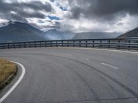 a highway stretches in the distance between two mountains, on a partly cloudy day with dark clouds