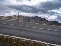 the mountain is covered in storm clouds while it stands alone on the edge of the highway