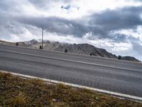 the mountain is covered in storm clouds while it stands alone on the edge of the highway