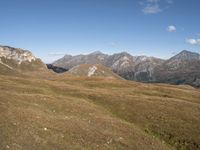 the grass is dying to the side of the mountains, with a mountain top in the distance