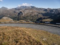 a blue train travels through the mountains and has a view of the mountains in the distance