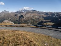 a blue train travels through the mountains and has a view of the mountains in the distance