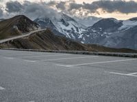 a road that is on the side of a mountain with snow capped mountains around it