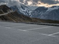 a road that is on the side of a mountain with snow capped mountains around it