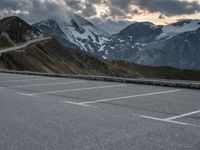 a road that is on the side of a mountain with snow capped mountains around it