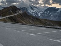 a road that is on the side of a mountain with snow capped mountains around it