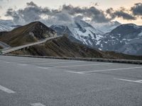 a road that is on the side of a mountain with snow capped mountains around it