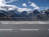 the mountains are covered with snow while the road passes by on a bridge across from them