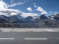 the mountains are covered with snow while the road passes by on a bridge across from them