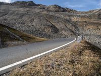 a road runs through a large rocky landscape with mountains in the distance, surrounded by barbed fence posts and rocks