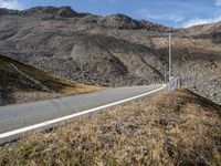 a road runs through a large rocky landscape with mountains in the distance, surrounded by barbed fence posts and rocks