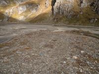 a person that is standing in the dirt with a motorcycle and backpack on a mountain slope