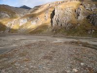 a person that is standing in the dirt with a motorcycle and backpack on a mountain slope