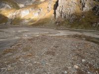 a person that is standing in the dirt with a motorcycle and backpack on a mountain slope