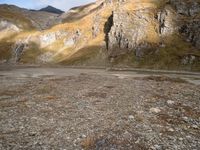 a person that is standing in the dirt with a motorcycle and backpack on a mountain slope