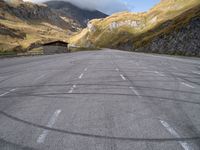 an empty parking lot in the middle of a mountainous area in europe with mountains in the background