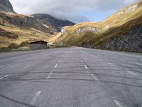 an empty parking lot in the middle of a mountainous area in europe with mountains in the background