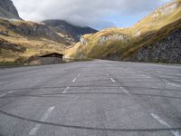 an empty parking lot in the middle of a mountainous area in europe with mountains in the background