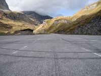 an empty parking lot in the middle of a mountainous area in europe with mountains in the background