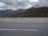 a view of a highway with an empty road on it with mountains in the background