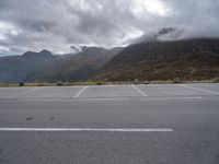 a view of a highway with an empty road on it with mountains in the background