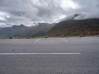 a view of a highway with an empty road on it with mountains in the background