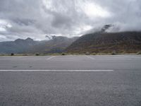 a view of a highway with an empty road on it with mountains in the background