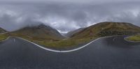 two winding roads with mountains in the background and a sign pointing up at each other